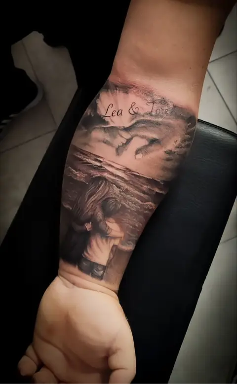Tatuaggio sull'avambraccio: due figure abbracciate davanti al mare, mani che si sfiorano sopra l'orizzonte e la scritta «Lea & Tore».