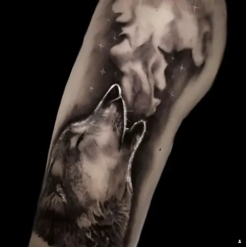 Tatuaggio sul polpaccio: un lupo in nero e grigio sotto una luna piena.
